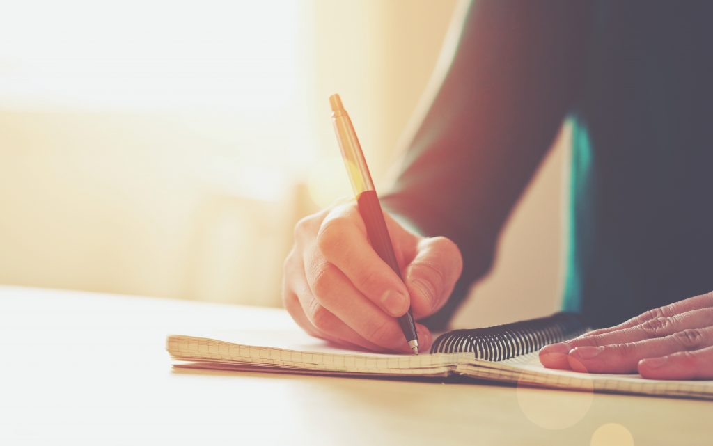 female hands with pen writing on notebook